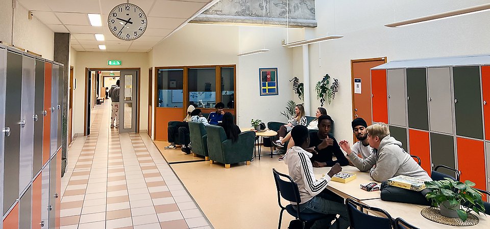 Elever sitter i ett utrymme i skolan och hänger på rasten.